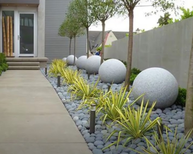 Garden path lined with round stone features and ornamental grasses