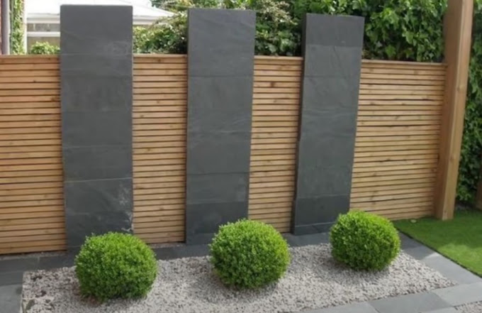 Tall slate garden screen panels against a timber slat fence with trimmed hedges
