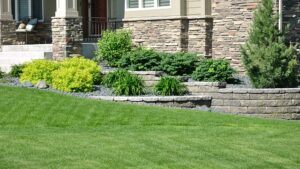 Low stone retaining wall with tiered garden beds along a front lawn