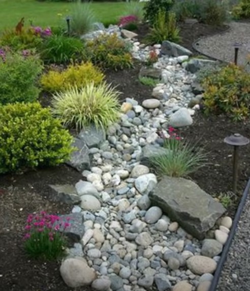 Dry creek bed garden feature with river stones and native plantings